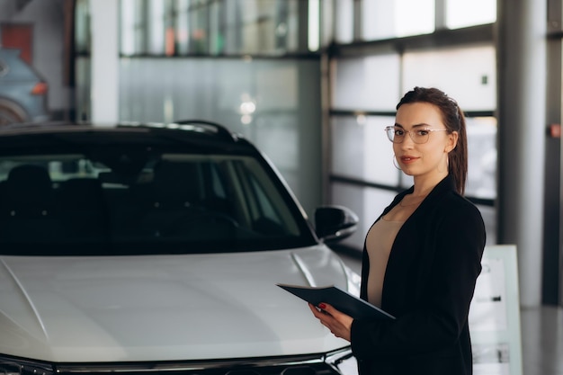 sozinha vendedora de carros bonita em terno segurando clipboard em novo showroom de carros conceito de automóvel