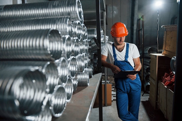 Sozinho no depósito. Homem de uniforme trabalha na produção. Tecnologia industrial moderna.