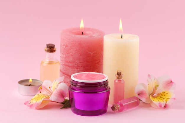 Spa. Aromaterapia. Cosméticos para el cuidado del cuerpo. Aceites aromáticos y crema sobre un suave fondo rosa.