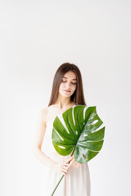 Spa y belleza. Autocuidado y cuidado de la piel. Feliz hermosa mujer en ropa acogedora sosteniendo una hoja de monstera verde