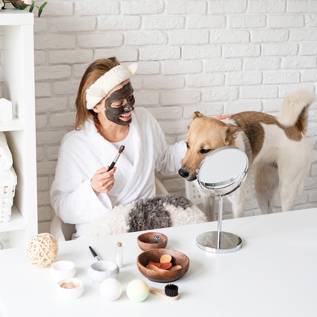 Spa y bienestar. Cosmética natural. Autocuidado. Joven mujer caucásica vistiendo albornoces haciendo procedimientos de spa con su perro