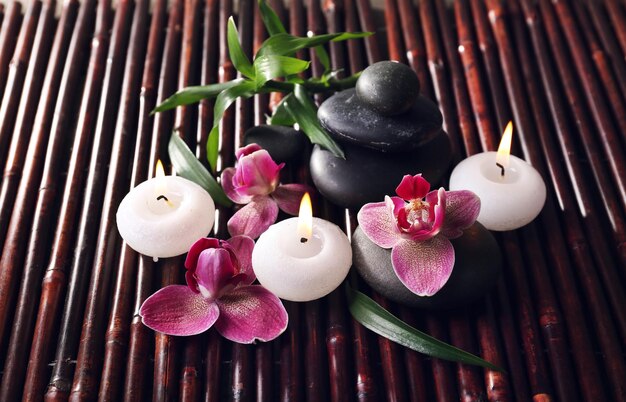 Spa bodegón con hermosas flores y velas sobre fondo de palos de bambú