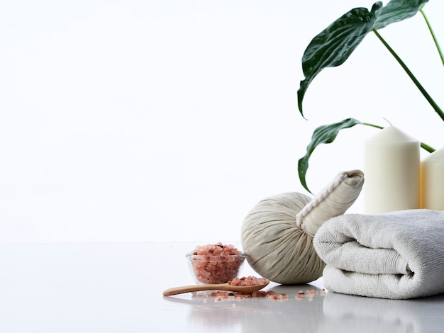 Spa concepto de masaje, bola de compresa herbal, crema, jabón de flores, vela perfumada y sal rosa del Himalaya, aislada