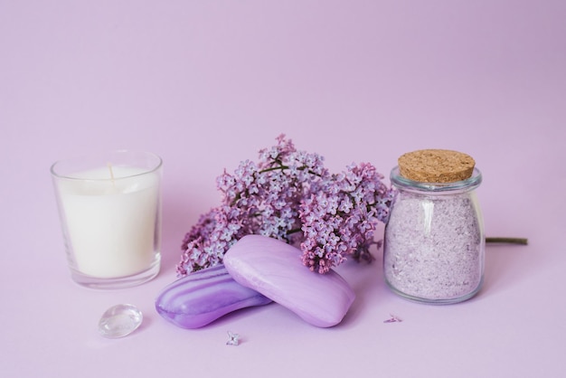 Spa-Einstellung mit lila Blüten Meersalz in einem Glas Seife und Kerze auf dem Hintergrund