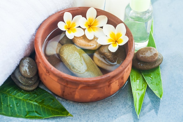 Spa flores tropicais e pedras e toalha branca para tratamento de massagem em fundo de mármore azul