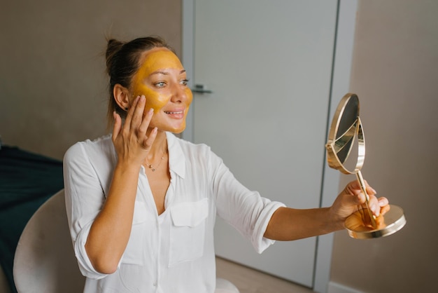 Spa-Frau setzt eine goldene Maske auf ihr Gesicht Schönheitsbehandlungen zu Hause