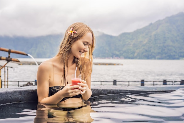 Spa geotérmico Mujer relajándose en la piscina de aguas termales contra el concepto de aguas termales del lago Beber jugo de guayaba