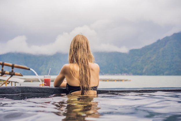 Spa geotérmico Mulher relaxante na piscina de águas termais contra o conceito de fontes termais do lago