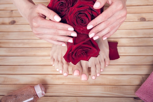 SPA. Hautpflege von weiblichen Händen und Füßen einer Schönheit mit roten Rosen, Tuch und Creme