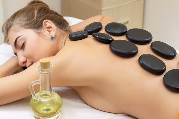 Spa Hot Stone Massage. Attraktives schönes Mädchen, das auf Massagebett im Spa-Salon liegt. Spa-Aromatherapie und Schönheitsbehandlungskonzept