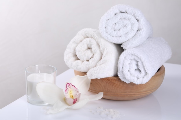 Spa-Komposition mit Handtüchern, Orchideenblumen, Kerze und Meersalz auf weißem Tisch