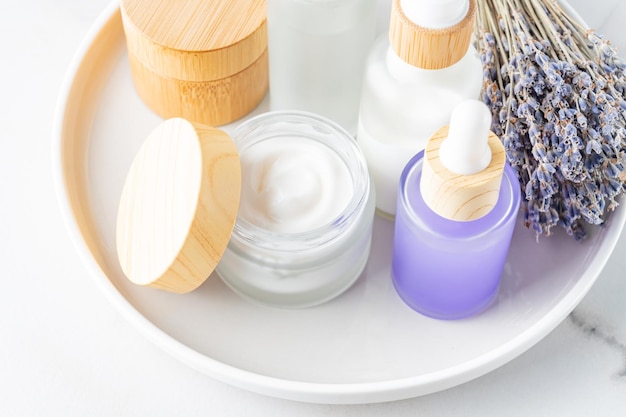 Spa de lavanda Ramo de flores crema corporal y aceite esencial Cosméticos de hierbas naturales con flores de lavanda sobre fondo de mármol Concepto de relajación Tratamientos de belleza Mockup