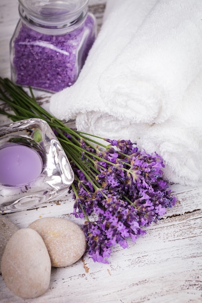 Spa de lavanda con rebbles, velas y toallas blancas.