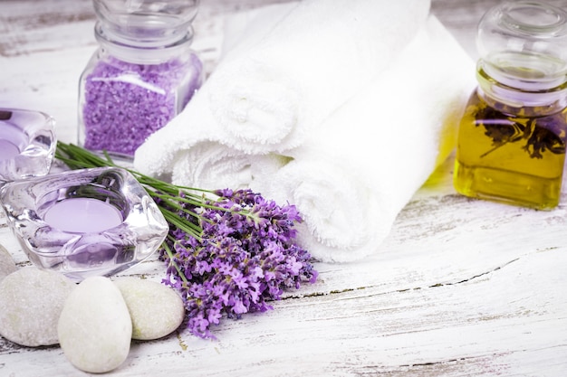 Spa de lavanda con rebbles, velas y toallas blancas.