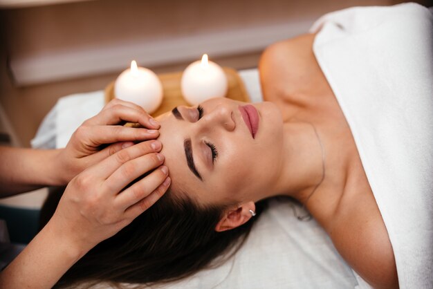 Spa. Mulher desfrutando de massagem facial anti-envelhecimento.