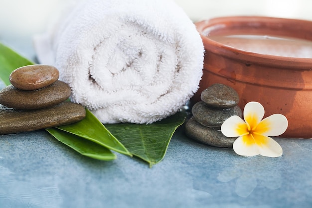 Spa orgánico Flor y hojas con piedras para masajes sobre fondo azul.