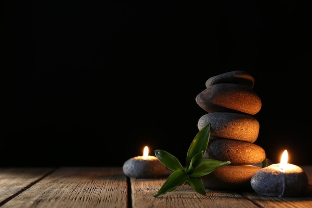 Spa pedras velas na mesa de madeira em fundo escuro