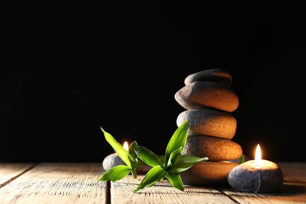 Spa pedras velas na mesa de madeira em fundo escuro