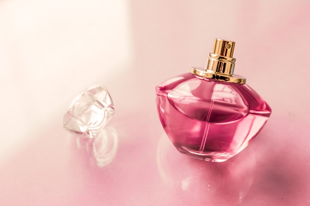 Spa de perfumería y concepto de marca botella de perfume rosa sobre fondo brillante fragancia de glamour de aroma floral dulce y eau de parfum como regalo de vacaciones y diseño de marca de cosméticos de belleza de lujo