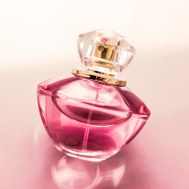 Spa de perfumería y concepto de marca botella de perfume rosa sobre fondo brillante fragancia de glamour de aroma floral dulce y eau de parfum como regalo de vacaciones y diseño de marca de cosméticos de belleza de lujo