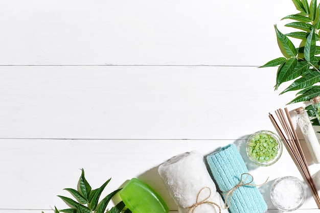 Spa-Produkte Badesalz Seifenkerzen und Handtuch flach auf weißem Holzhintergrund Draufsicht legen