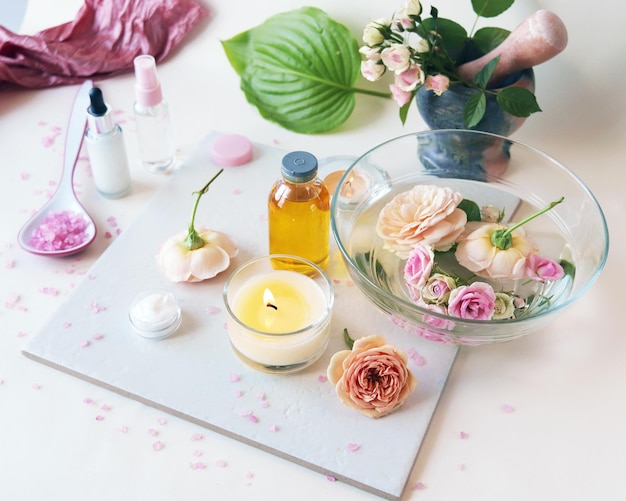 Spa rosas rosadas frescas quemando velas aceites y tinturas sobre un fondo claro estilo de vida saludable