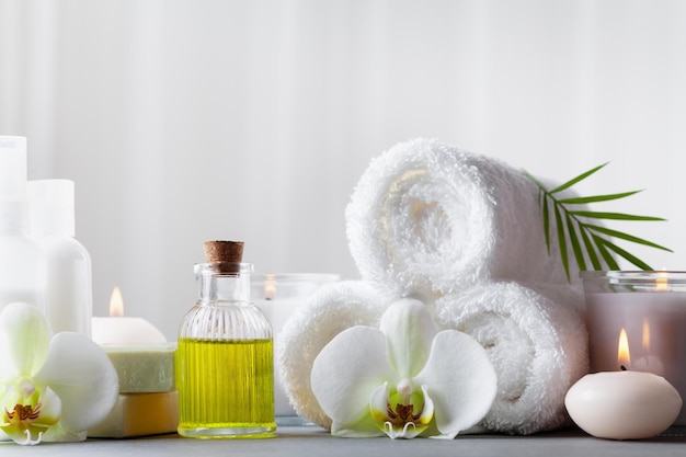 Spa-Schönheitsbehandlung und Wellness-Hintergrund mit Massageöl, Orchideenblüten, Handtüchern, Kosmetikprofi