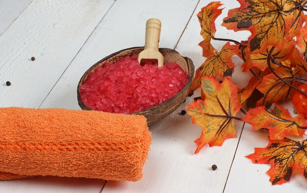 Spa situado em uma mesa de madeira branca e perto das folhas de bordo de outono laranja