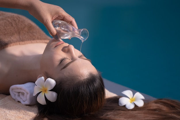 Spa terapia de masajes y cuerpo con aceite junto a la piscina.