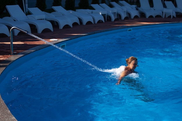 Spa-Therapie Eine ältere Frau genießt eine Rücken- und Nackenmassage mit einem Wasserstrahl im Pool bei einem heißen...