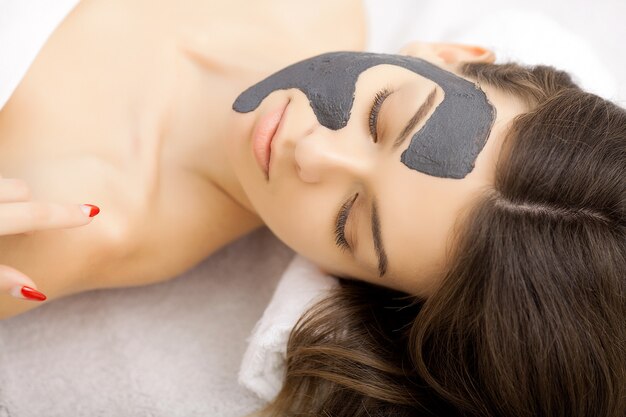 Spa-Therapie für junge Frau mit Gesichtsmaske im Schönheitssalon
