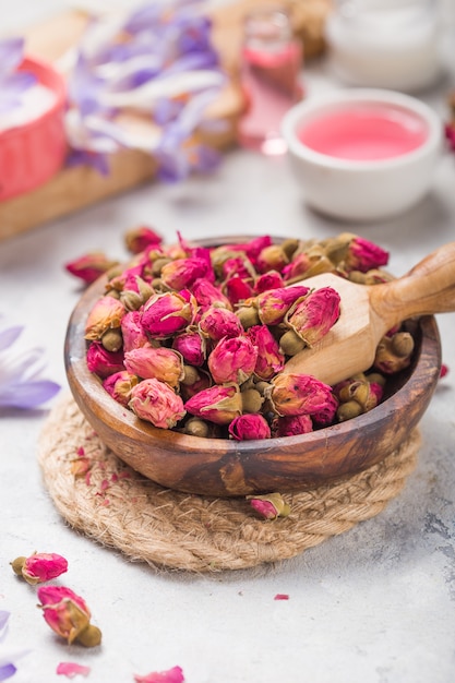 Spa- und Wellnesskonzept mit trockenen Rosen, rosa Öl und Milch auf Betonhintergrund.