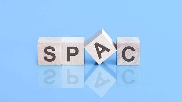SPAC-Symbol. Holzklötze mit den Worten "SPAC, spezielle Akquisitionsfirmen" auf schönem blauem Hintergrund, Kopierraum. Geschäftskonzept.