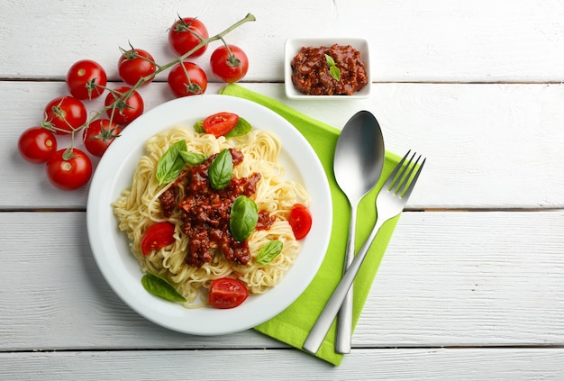 Spaghetti Bolognese auf weißer Platte auf farbigem Holzhintergrund