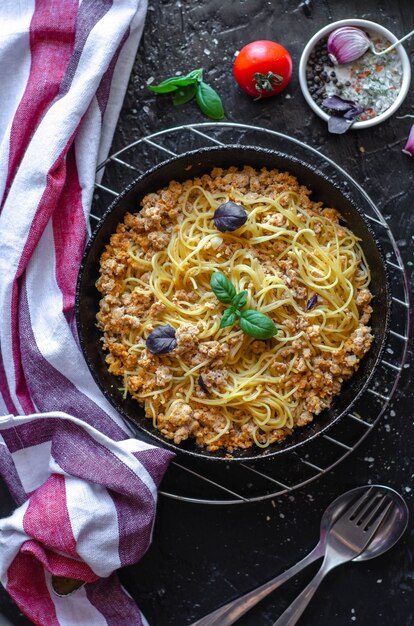 Spaghetti Bolognese in einer Pfanne auf dem Tisch serviert mit Tomaten, Knoblauch und Basilikum
