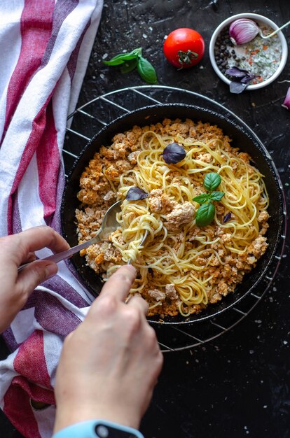 Spaghetti Bolognese in einer Pfanne auf dem Tisch serviert mit Tomaten, Knoblauch und Basilikum