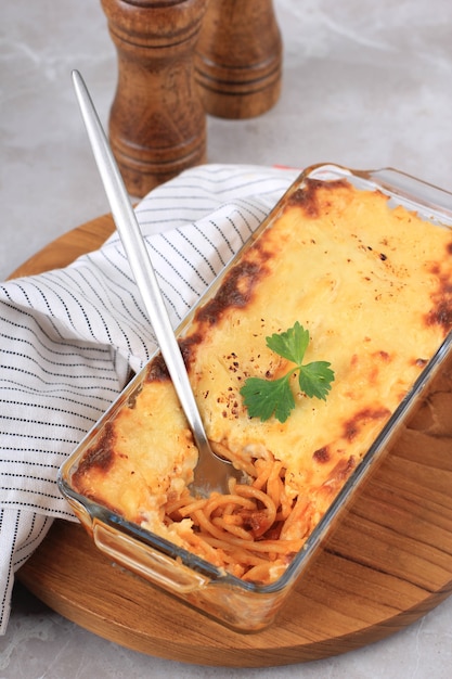 Spaghetti Brulle auf klarer Backform l mit Edelstahllöffel und Gabel hautnah. Spaghetti Brulee sind gebackene Spaghetti mit Bechamel- und Bolognese-Sauce. Ausgewählter Fokus