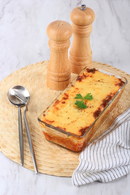 Spaghetti Brulle auf klarer Backform l mit rostfreiem Löffel und Gabel. Spaghetti Brulee sind gebackene Spaghetti mit Bechamel-Bolognese-Sauce