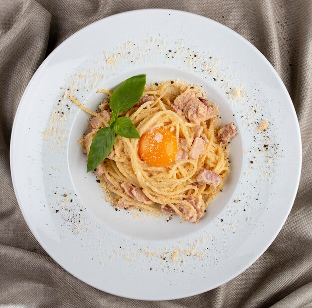 Spaghetti Carbonara auf weißer Platte auf Textilhintergrund