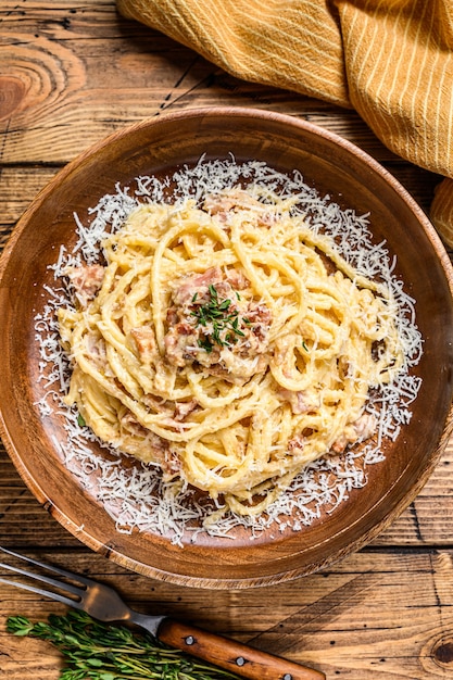 Foto spaghetti carbonara macarrão com pancetta, ovo, queijo parmesão duro e molho de natas. fundo de madeira. vista do topo.