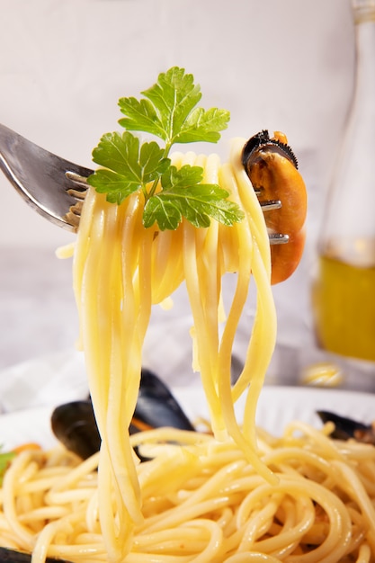 Spaghetti envuelto en un tenedor con mejillón, primer plano de spaghetti con mejillón de Taranto