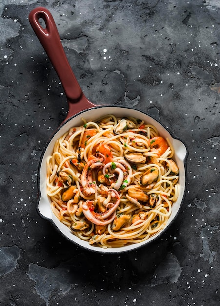 Spaghetti frutti di mare en una sartén sobre un fondo oscuro vista superior Deliciosa comida mediterránea tradicional