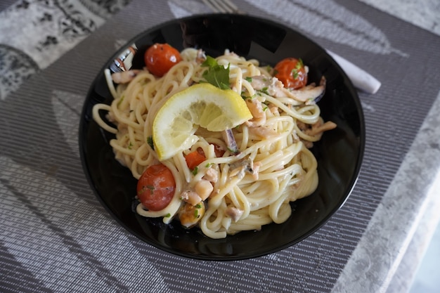 Spaghetti-Meeresfrüchte-Pasta mit Garnelen-Tomaten in einem schwarzen Teller