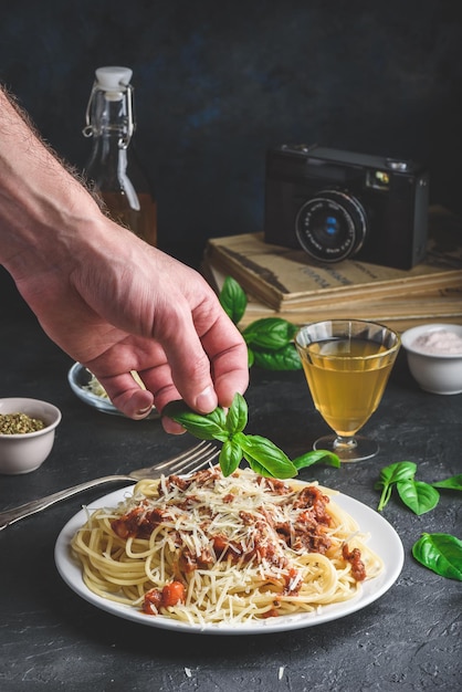 Spaghetti mit Bolognese-Sauce und geriebenem Parmesankäse. Fertiggericht mit Basilikumblättern von Hand garnieren