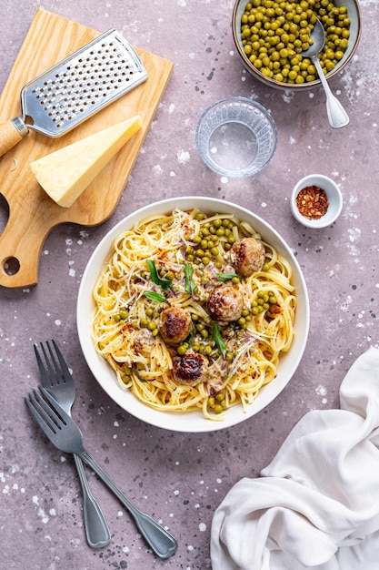 Foto spaghetti mit fleischkugeln und sahnesauce wird auf einem teller mit kräutern und parmesan serviert