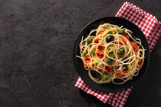 Spaghetti mit gemüsebrokkolitomatenpaprika auf schwarzem hintergrund