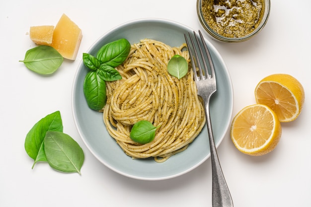 Spaghetti mit Pesto-Sauce und Basilikum in Schüssel auf weißem Hintergrund