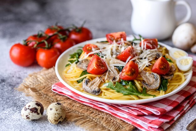 Spaghetti mit Pilzen, Käse, Spinat, Rukkola und Kirschtomaten. Italienisches Gericht, mediterrane Kultur