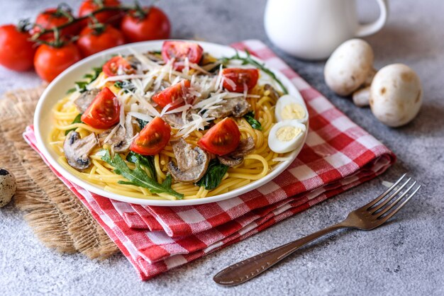 Spaghetti mit Pilzen, Käse, Spinat, Rukkola und Kirschtomaten. Italienisches Gericht, mediterrane Kultur