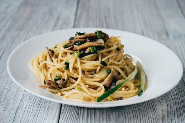 Spaghetti mit Pilzen und Zwiebeln auf einer weißen Platte